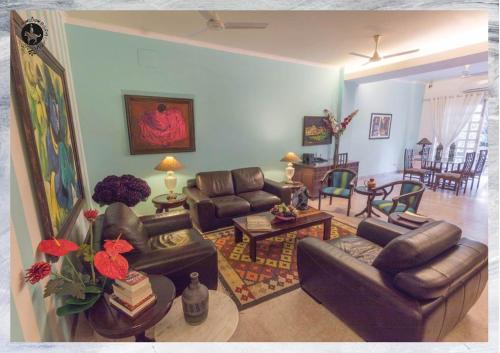a living room with leather couches and a living room with a table at Colonel’s Retreat in New Delhi