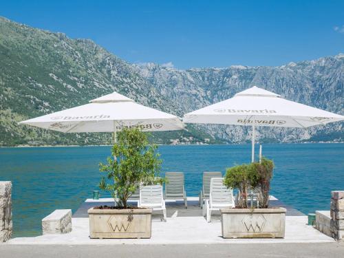 two white umbrellas and chairs and a lake at Apartments Iva in Kotor