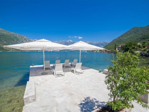 a patio with chairs and umbrellas on the water at Apartments Iva in Kotor