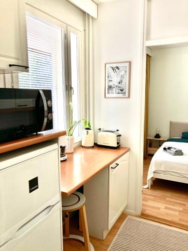 a kitchen with a desk with a microwave and a bed at Moomin Lover Home in Central Helsinki - Pool & Sauna in Helsinki