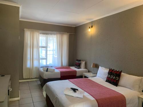 a hotel room with two beds and a window at Cockpit Guest House Kempton Park Airport Getaway in Kempton Park