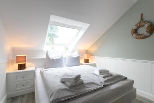 a bedroom with a bed with white sheets and a window at Top gelegenes Apartment Dünenstuuv direkt im Zentrum von SPO in Sankt Peter-Ording