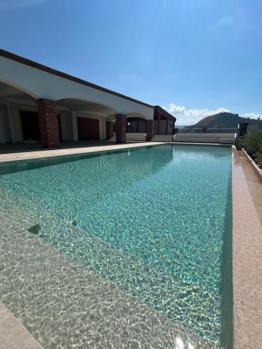a swimming pool with blue water in front of a building at Chalet Tenuta Lacco in Furnari