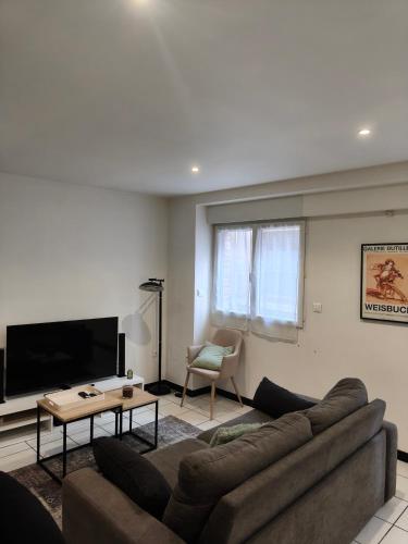 a living room with a couch and a flat screen tv at Les Pierres de Rinaldi in La Celle-sous-Gouzon