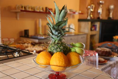 a bowl of fruit on a counter with a pineapple at Villa Manno in Barcellona-Pozzo di Gotto