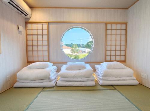 a room with three beds and a round window at Fujiyoshida house, 2 toilet 2 bathroom, Mt Fuji view, 4 living room, free parking 5 cars, projector, washmachine, pet ok in Minamitsuru