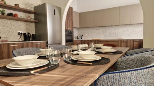 a wooden table with chairs and plates and glasses at Spacious & Sunlit Charm in Malta! in Siġġiewi