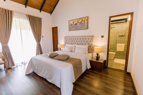 a bedroom with a large white bed and a shower at Chaza Oddington in Lindula