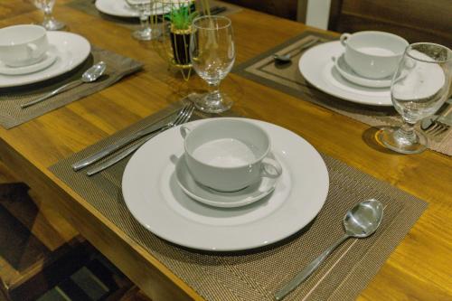 a wooden table with white plates and silverware on it at Chaza Oddington in Lindula