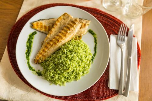 a plate of food with fish and green risotto at Pensiunea Sibiel in Sibiel