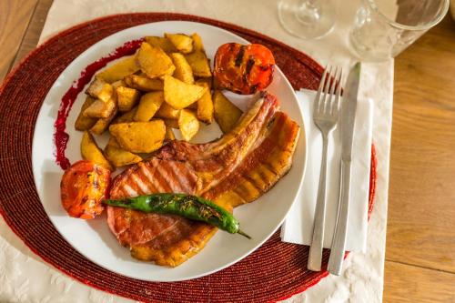 a plate of food with meat and potatoes on a table at Pensiunea Sibiel in Sibiel