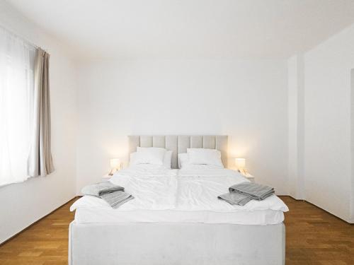 a white bed in a white room with two lamps at Cozy Apartment Szentendre in Szentendre