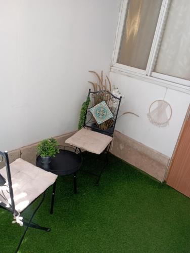 a small balcony with a table and chair and green carpet at מקסימה עם חצר במרכז העיר in Eilat