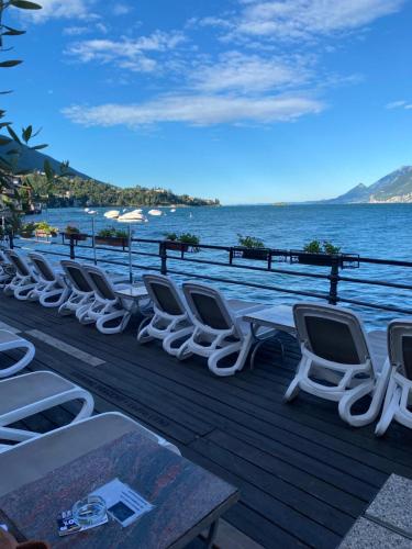 a row of chairs and tables on a deck next to the water at Hotel Malcesine in Malcesine
