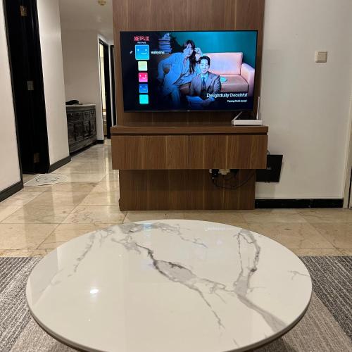 a marble table in front of a flat screen tv at Apartment 3 BR Luxurious Braga Citywalk in Bandung