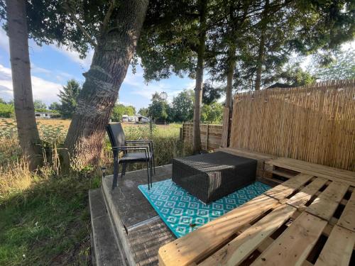 a wooden bench with a chair next to a tree at Ibiza chalet in natuurlijke omgeving in Bergen op Zoom