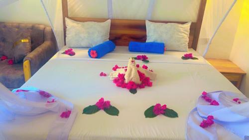 a white bed with pink flowers on it at The Dream Village in Kiwengwa