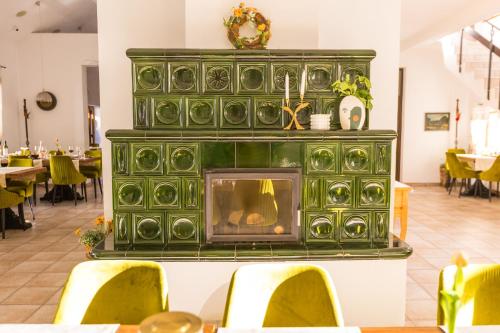 a green fireplace in a restaurant with tables and chairs at Pensiunea Sibiel in Sibiel