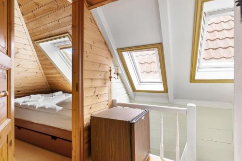 a small attic room with a bed and two windows at City Center Gem I Traditional Bergen Style in Bergen