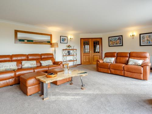 a living room with brown leather couches and a table at Ard Taigh in Stron-fearnan