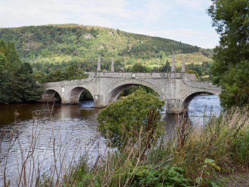 a stone bridge over a river with a mountain at Ard Taigh in Stron-fearnan