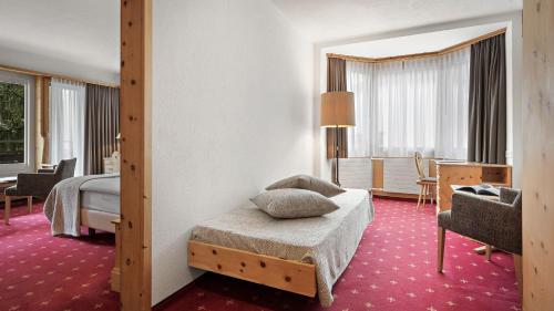a hotel room with a bed and a living room at Morosani Posthotel in Davos