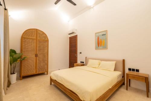 a bedroom with a bed and a wooden cabinet at Casa Kesari Sanur Villa in Sanur