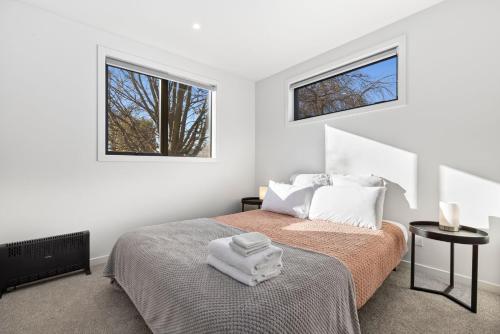 a white bedroom with a bed and two windows at BRAND NEW - Wanaka Studio in Wanaka