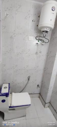 a white bathroom with a toilet and a light at Raj Residency Chhatarpur in New Delhi