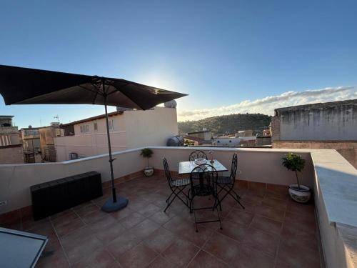eine Terrasse mit einem Tisch und einem Sonnenschirm auf dem Balkon in der Unterkunft Angelica's House in Noto