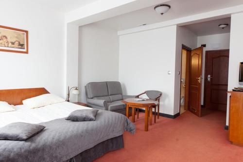 a bedroom with a bed and a chair and a table at Piwnica Rycerska Kęty in Kęty