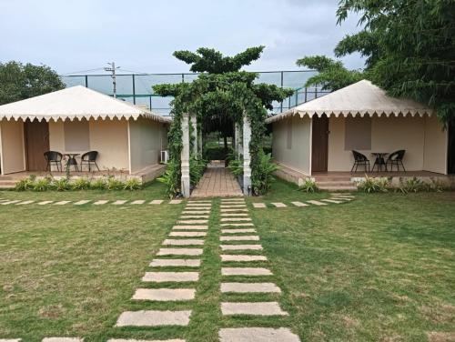a walkway leading to two bungalows in a yard at Hasiru Bhoomi Resort 