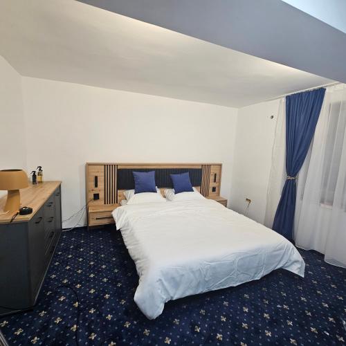 a bedroom with a large white bed with blue pillows at Hotel Hermes in Eforie Nord