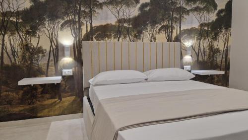 a bedroom with a white bed with trees on the wall at L'Arte del Porto in Catania