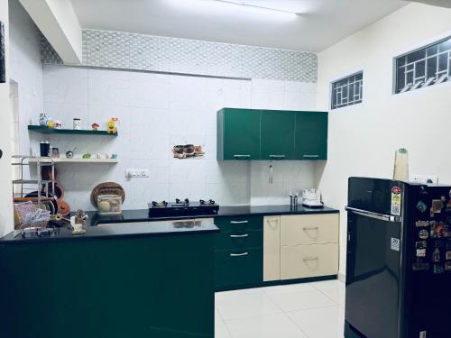a kitchen with green cabinets and a black refrigerator at Room availbale in 2 bhk apartment in Bengaluru