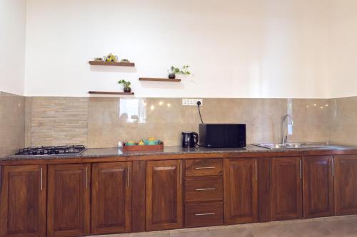 a kitchen with wooden cabinets and a sink at The Teak Ambalangoda in Ambalangoda