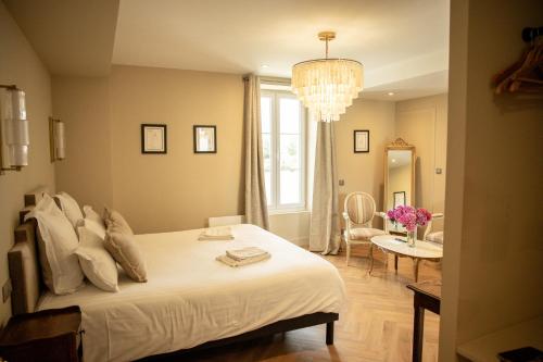 a bedroom with a white bed and a chandelier at Domaine du Grand Caugy in Saint-Vigor-le-Grand