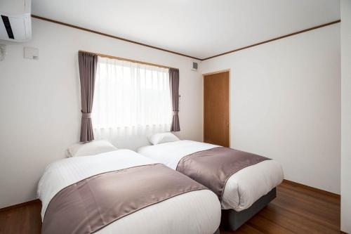 Dos camas en una habitación con ventana. en Fuji Mason's Villa, en Fujiyoshida