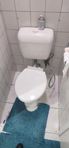 a white toilet in a bathroom with a blue rug at Room with King Single bed in Melbourne