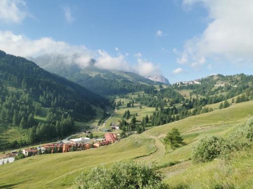 a green hillside with a village and mountains in the background at Shackleton Chalet in Sestriere
