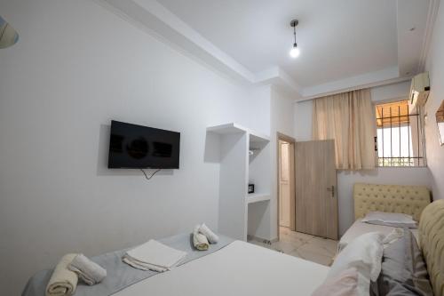 a white room with a bed and a tv on the wall at Andy Apartments in Sarandë