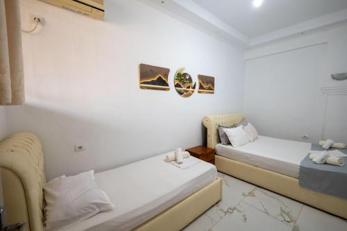 two beds in a room with white walls at Andy Apartments in Sarandë