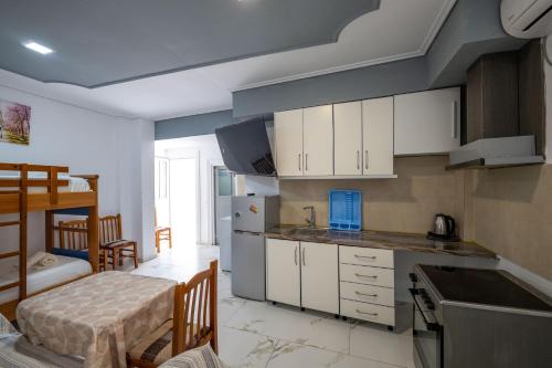 a kitchen with white cabinets and a bed in a room at Andy Apartments in Sarandë