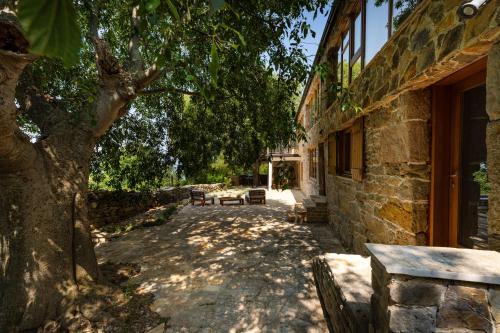 a stone building with a bench next to a tree at Villa Pueblo Karin in Gornji Karin