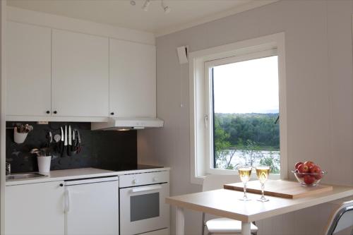 a kitchen with white cabinets and a table with two glasses of wine at Tana Panorama Apartments in Skiippagurra