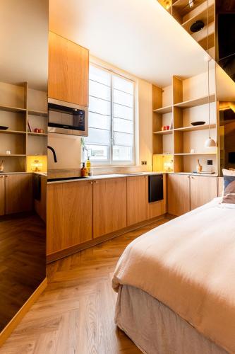 a bedroom with a bed and a kitchen with a window at Studio moderne tout confort aux portes de Paris à Saint-Ouen in Saint-Ouen