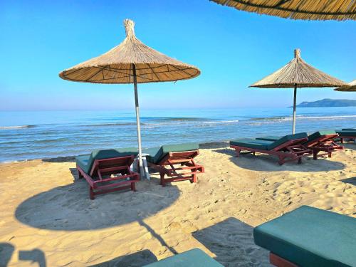 a group of chairs and umbrellas on a beach at Cozy Beach Apartment - 296 in Durrës
