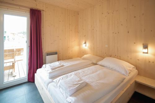 a large bed in a room with a large window at Woody Park Feriendorf Murau in Murau