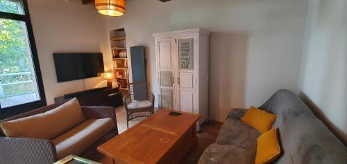 a living room with a couch and a table at Maison Normande au bord de rivière avec spa et sauna in Rugles