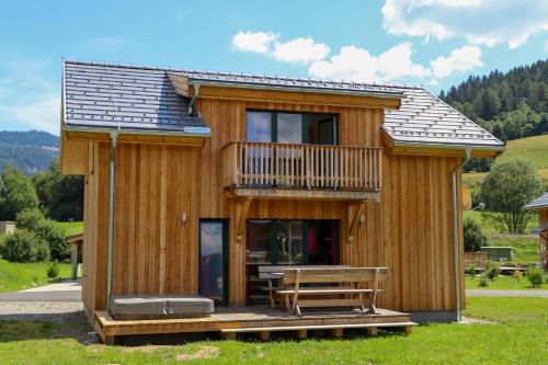 a wooden cabin with a deck and a table at Woody Park Feriendorf Murau in Murau